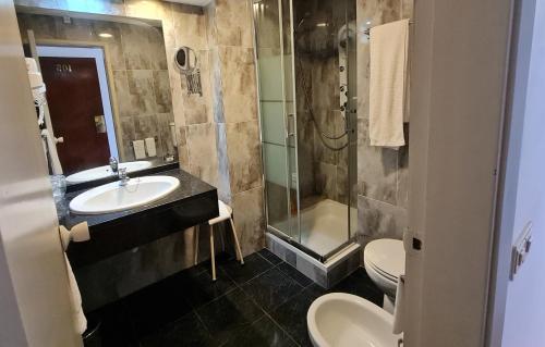 a bathroom with a sink and a shower and a toilet at Hotel Eden in Luso