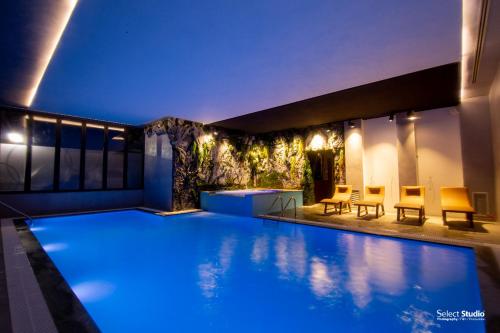 a swimming pool at night with chairs and tables at Hotel Kocibelli POOL & SPA in Korçë