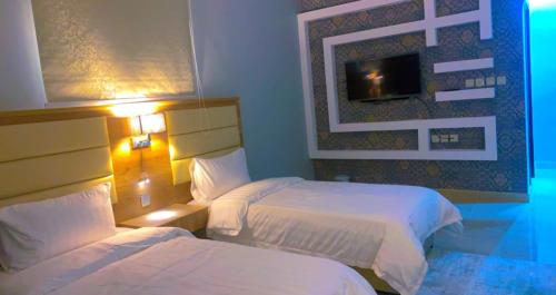 a hotel room with two beds and a tv at شقق Flower-z in Al-ʿUla