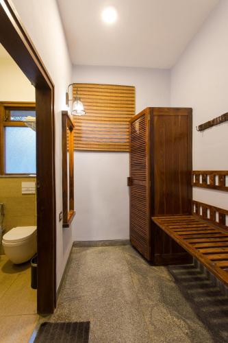 a bathroom with a toilet and a wooden door at Heritage Resort Hampi in Hampi