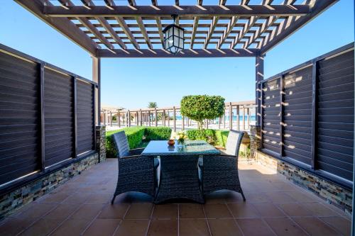 a patio with a table and chairs under a pergola at Danat Jebel Dhanna Resort in Jebel Dhanna