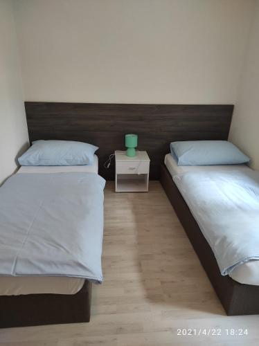 two beds in a bedroom with a green vase on a night stand at Apartmani QUATTRO in Starigrad
