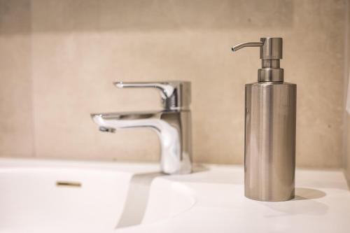 a metal soap dispenser sitting on a bathroom sink at Hotel Lehn in Nieder-Saulheim