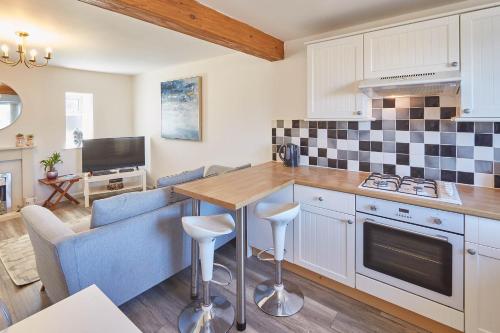 a kitchen with white cabinets and a table with stools at Host & Stay - Robins Den in Whitby