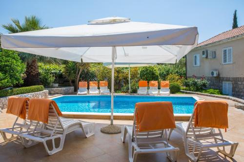 a white umbrella and two chairs and a pool at Apartments Vidak in Molunat