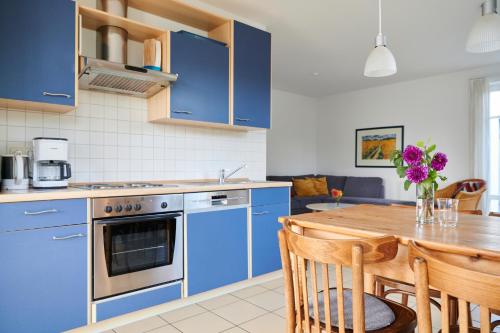 uma cozinha com armários azuis e uma mesa de madeira em Sonneneck Rerik em Rerik