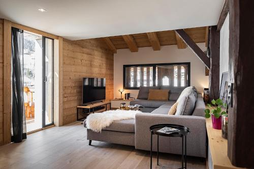uma sala de estar com um sofá e uma televisão em Spacieux duplex avec vue em La Clusaz