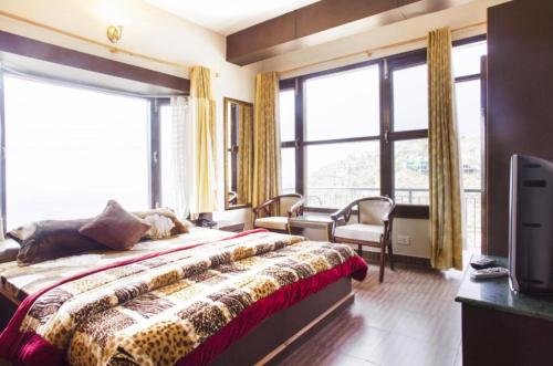 a bedroom with a bed and a tv and windows at Kasauli Residency in Kasauli