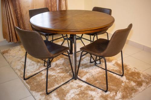 drewniany stół i cztery krzesła na dywanie w obiekcie Lodwar Acacia Residences w Lodwar