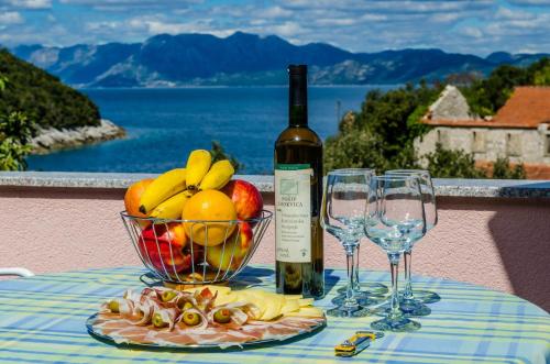 einen Tisch mit einer Schale Obst und einer Flasche Wein in der Unterkunft Apartment Bay of Dreams in Janjina