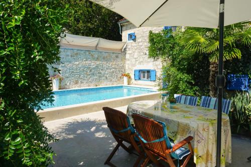 een tafel met stoelen en een parasol naast een zwembad bij Vila Vinci 1906 in Vrsar