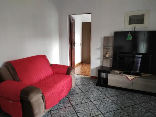 a living room with a red couch and a television at Quarto duplo aconchegante com banheiro privativo, ambiente inteiro in Barueri