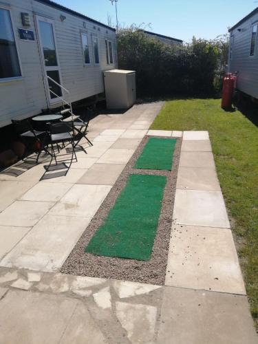 a patio with green grass and a table and chairs at Manor Park Hunstanton pets go free Linen Included in Hunstanton