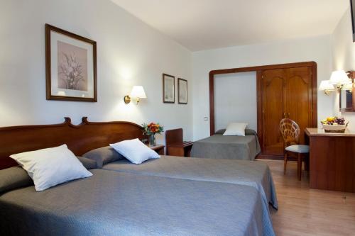 a hotel room with two beds and a desk at Gaudi Hotel in Barcelona