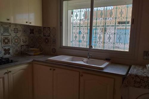 una cucina con lavandino e finestra di Dar Mohcen a Ajim