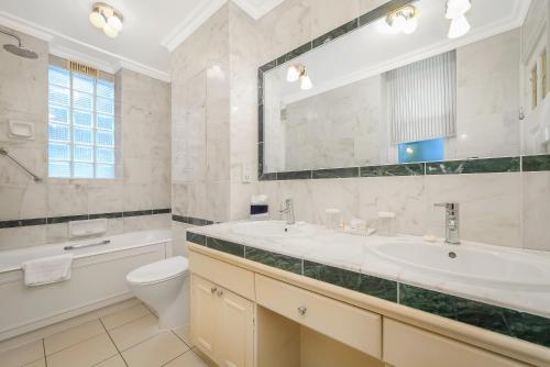 a bathroom with a sink toilet and a mirror at 44 Curzon Street by Mansley in London