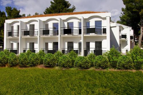 a white building with a balcony and bushes at Ville Imperial Vodice in Vodice
