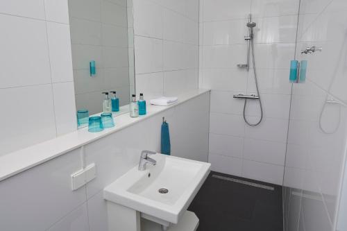 a white bathroom with a sink and a shower at Bed & Breakfast Hotel Malts in Haarlem