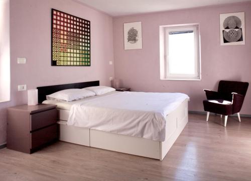 a bedroom with a large white bed and a chair at Hana place in Motovun
