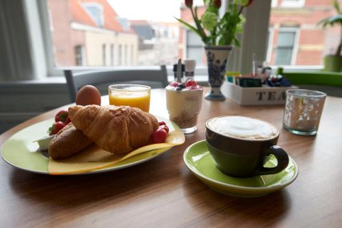 a table with a plate of food and a cup of coffee at Bed & Breakfast Hotel Malts in Haarlem