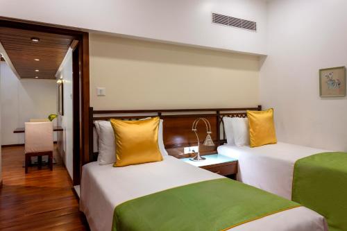 a hotel room with two beds with yellow and green sheets at Caravela Beach Resort in Varca
