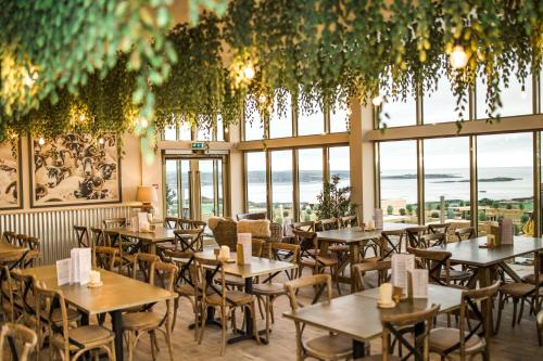 restauracja ze stołami i krzesłami w pokoju z oknami w obiekcie Sea View Snugs at Laggan w mieście Gatehouse of Fleet