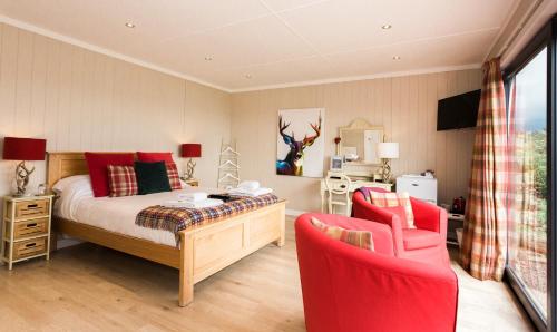 a bedroom with a bed and two red chairs at Sea View Snugs at Laggan in Gatehouse of Fleet