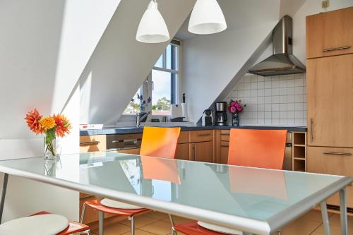 eine Küche mit einem Glastisch und orangefarbenen Stühlen in der Unterkunft Haffblick Rerik in Rerik