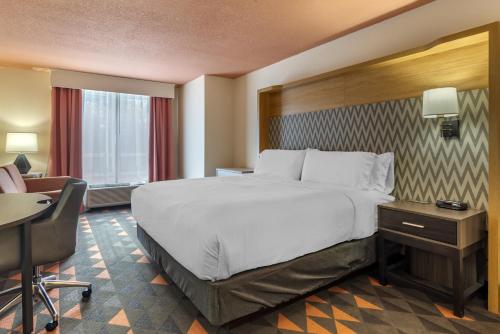 ein Hotelzimmer mit einem großen Bett und einem Schreibtisch in der Unterkunft Holiday Inn Atlanta-Gas South Arena Area, an IHG Hotel in Duluth