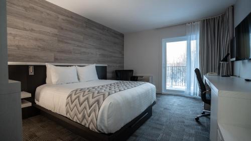 a hotel room with a bed and a desk and a window at Hôtel Le Francis in New Richmond