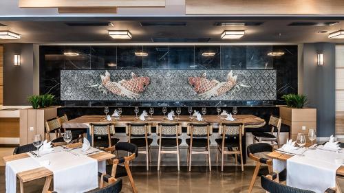 a dining room with tables and chairs and a wall at Avra Imperial Hotel in Kolymvari