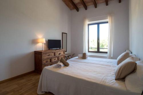a white bedroom with a large bed and a television at Finca Can Peixet in Manacor