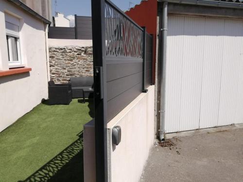 a gate to a house with a yard with green grass at La Petite Maison in Brest