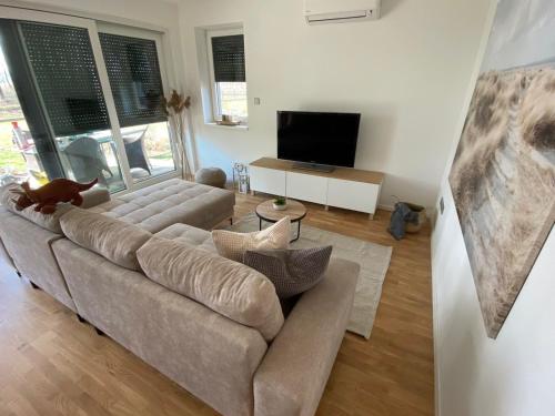 a living room with a couch and a flat screen tv at Fűzliget Terrace in Balatonfůzfő