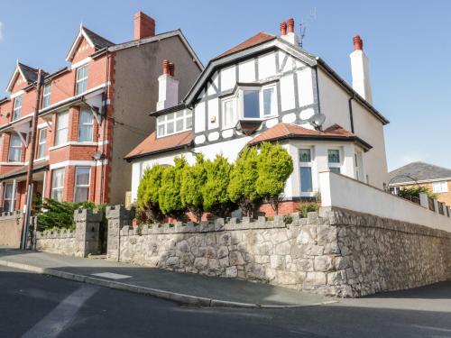 a white house with a stone wall and trees at Beausite in Colwyn Bay