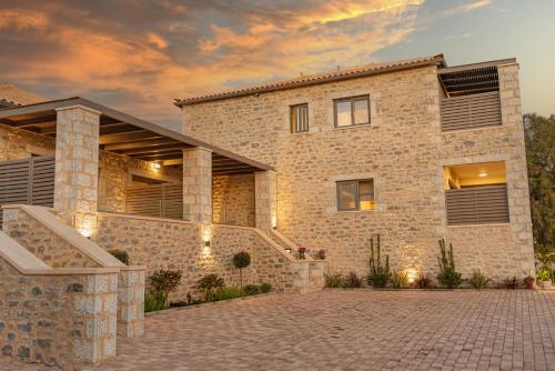 a large stone house with a brick driveway at Linari Villas in Stoupa