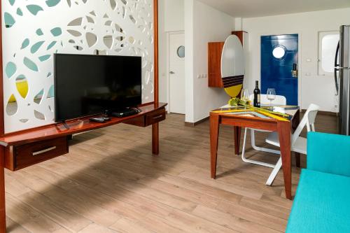 a living room with a television and a desk with a table at Puerto Plaza Las Terrenas in Las Terrenas