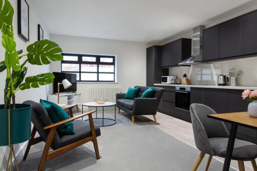 a kitchen and living room with black cabinets at Queens Park by Viridian Apartments in London