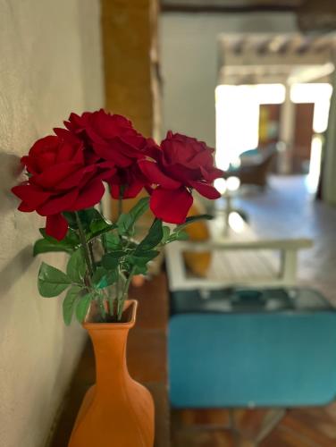 an orange vase with red roses in a living room at Casona CHARA in Barichara