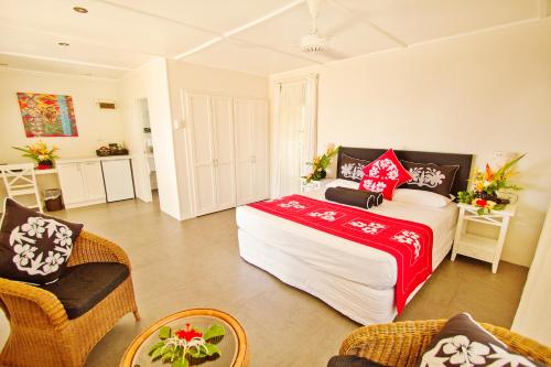 a bedroom with a bed and chairs in a room at Manuia Beach Resort in Rarotonga