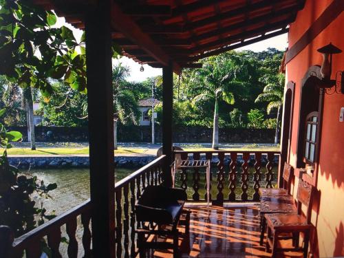 a porch of a house with a table and chairs at Pousada Casa do Rio Hostel - 8 min do Centro Hístorico in Paraty