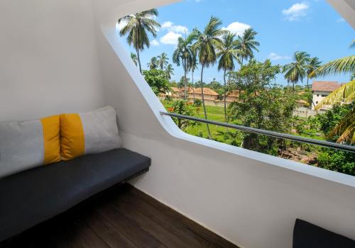 a balcony with a couch and a window with palm trees at Puerto Plaza Las Terrenas in Las Terrenas