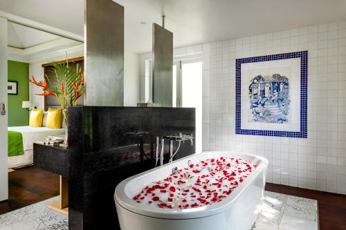 a bathroom with a bath tub covered in red rose petals at Caravela Beach Resort in Varca