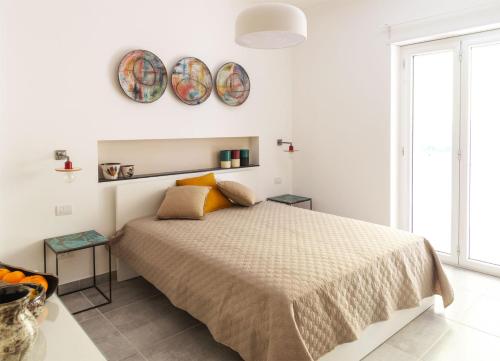 een witte slaapkamer met een bed en twee borden aan de muur bij Damè - Accommodation Amalfi Coast in Maiori