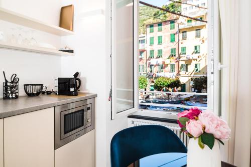 a kitchen with a blue chair and a window at MADA Charm Apartments Piazza in Vernazza