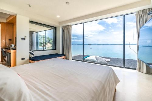 a bedroom with a large white bed and a large window at 8IK88 Resort, Phuket - SHA Extra Plus in Por Bay