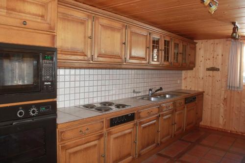 a kitchen with wooden cabinets and a sink and a microwave at Chalet Suisse Authentique in La Comballaz