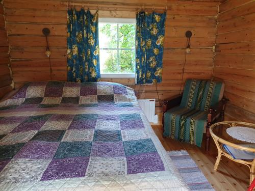 een slaapkamer met een bed, een raam en een stoel bij Nestorinranta Resort in Lintusalo