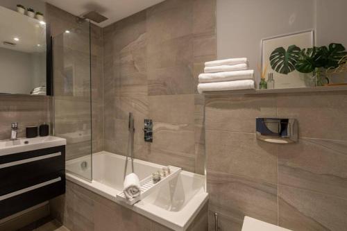 y baño con ducha, bañera y lavamanos. en Roseland Apartment 1, en Arundel