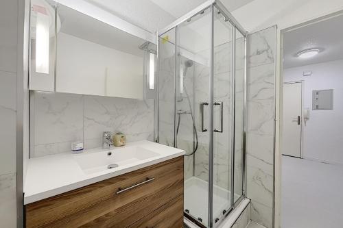 une salle de bain blanche avec un lavabo et une douche dans l'établissement Studio Cosy Les Jardins de la Mer, à Sainte-Maxime